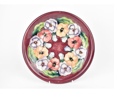 A Moorcroft ceramic Pansy plate designed by Rachel Bishop, with impressed marks and signature to the underside, 26 cm diamete