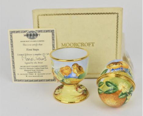 A limited edition Moorcroft Enamels Ltd 'First Steps' egg cup and hinged egg painted by Marie Graves depicting chicks in a ga