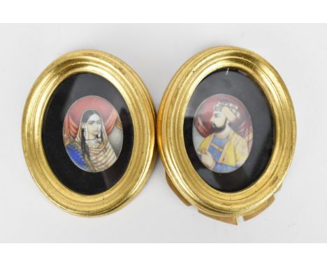 A pair of hand painted Indian portrait miniatures on ivory, depicting a Maharajah and Maharani in rich jewelled clothing with