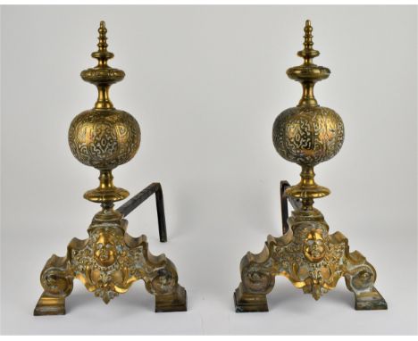A large pair of English 19th century or earlier brass and iron firedogs, with central mask flanked by dolphins on divergent f
