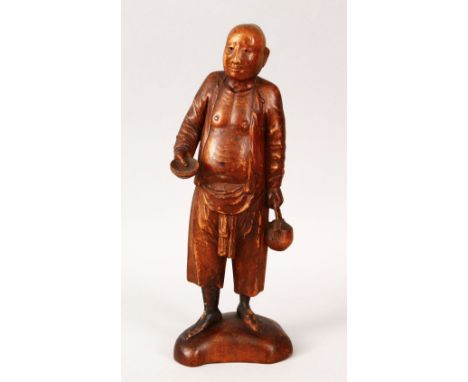 A 19TH / 20TH CENTURY CHINESE BOXWOOD CARVED FIGURE OF A MAN, the man holding a teapot in one hand and a bowl in the other, 2