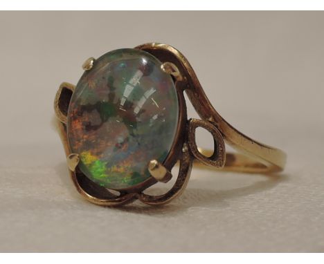 A lady's dress ring having an oval opal doublet in a stylised claw set mount on a yellow metal loop stamped 585/14K,  size S