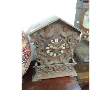 An early/mid 20th oak mantel cuckoo clock in the Black Forest style having carved fruit and vine decoration