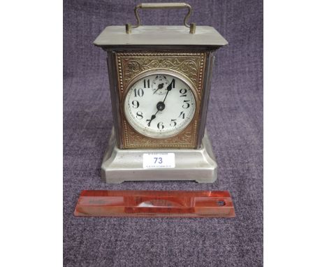 An Edwardian metal and brassed mantel clock of Continental music box design having embossed decoration and circular face, mar