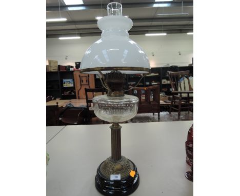 A late Victorian/Edwardian oil lamp having opaque glass shade over glass reservoir and brass column