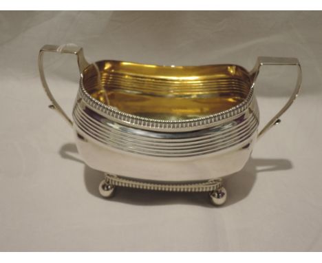 A Georgian silver sugar bowl of shaped oblong form having gadrooned rim, reeded decoration, architectural and quill handles, 