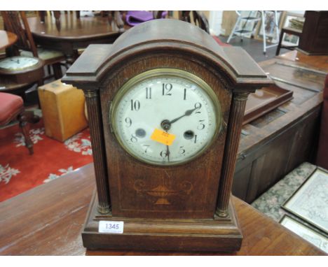A late Victorian oak mantel clock having corinthion pillar and urn inlay decoration, with circular dial and striking movement