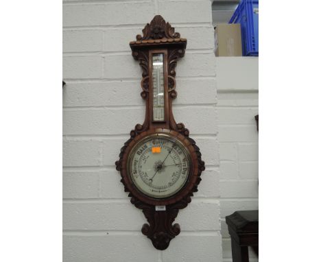 An Edwardian mahogany aneroid banjo having extensive carved decoration with thermometer scale