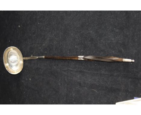 An 18th Century silver punch ladle, the white metal bowl set with a George II silver sixpence dated 1758, set on a twisted wh