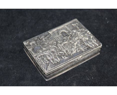 A 19th Century white metal snuff box, the lid with embossed decoration depicting classical figures worshipping a King/leader 
