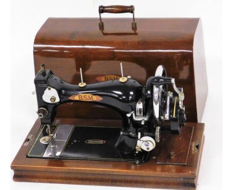An early 20thC Triumph manual sewing machine, in black on oak stained base, with cover, 36cm wide.