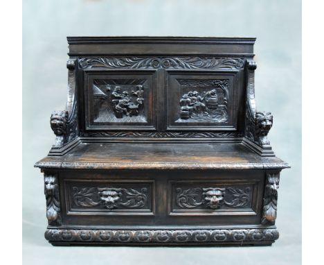 A Victorian oak box settle, the two panel back profusely carved in relief with tavern scenes, having scale carved downswept a