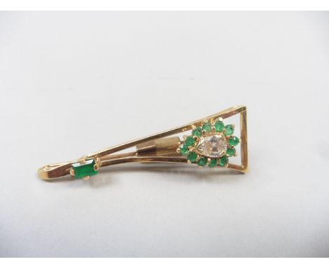 An 18ct gold stick pin set with a pear cut diamond surrounded by cut emeralds under a solitaire baguette cut emerald.