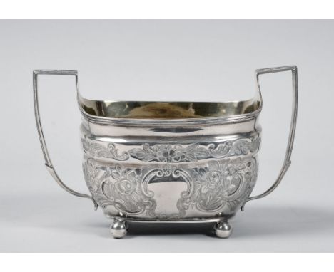A George IV two handled sucrier and a cream jug, both profusely embossed and engraved with flowers and scrollwork and support