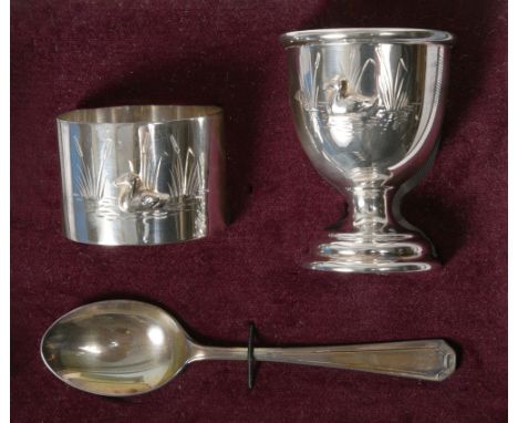 A contemporary  silver egg cup, napkin ring and spoon christening set with a duck on the water and bullrushes, makers mark fo