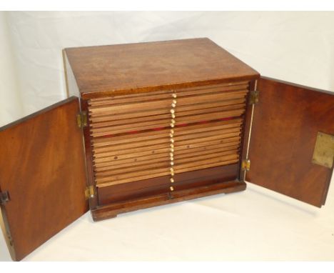 An old mahogany coin collector's cabinet with numerous shallow drawers and two base deeper drawers enclosed by two panelled d