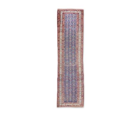 A North West Persian RunnerCirca 1920With field of three rows of diamond motifs on an indigo ground, 359cm long x 100cm wide 