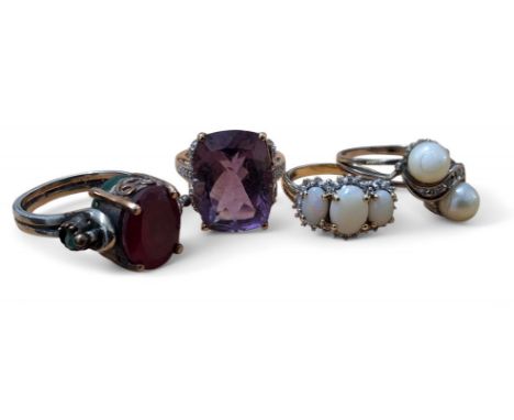 A 9ct gold and opal trilogy ring, set with a central oval opal, 7.6 x 5.6mm, flanked by two oval opals, 5.5 x 3.7mm, within a