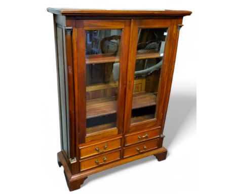 A modern teak display cabinet, two crossbanded glazed cupboard doors revealing shelves, flanked by gilt metal mounted Corinth