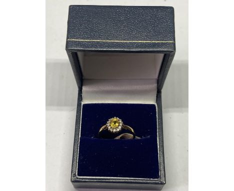 A 9 CARAT GOLD RING WITH CENTRECITRINE SURROUNDED BY CLEAR STONES SIZE K/L IN  A PRESENTATION BOX 