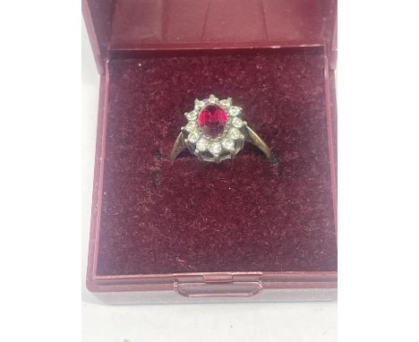 A SILVER RING WITH CENTRE RED STONE SURROUNDED BY CLER STONES IN A PRESENTATION BOX 