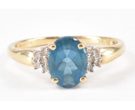 A hallmarked 9ct gold and topaz ring. The ring being set with an oval cut blue topaz flanked by ten diamond accents. Hallmark