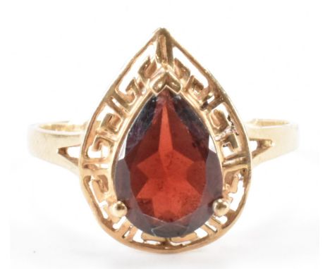 A vintage gold and garnet ring. The ring being set with a pear cut garnet set within a pierced greek key design mount. Marked