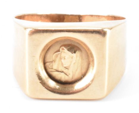 A vintage gold signet ring. The ring having a square head with a round panel depicting the virgin Mary, on a plain tapering b