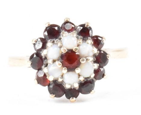 A vintage gold opal and garnet cluster ring. The ring having a central garnet circled by six opal cabochons and twelve garnet