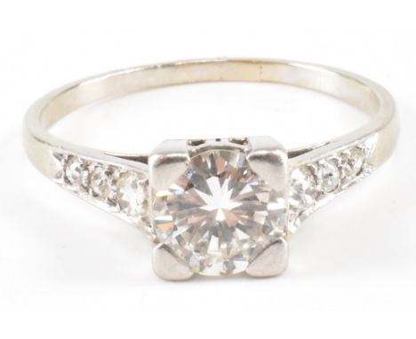 An Art Deco white gold and diamond solitaire ring. The ring being set with a round brilliant cut diamond in a square setting,