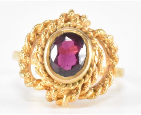 A vintage hallmarked 9ct gold and garnet ring. The ring being bezel set with an oval cut garnet with a pierced rope twist kno