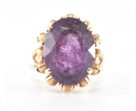 A hallmarked 9ct gold and amethyst dress ring. The ring being set with an oval cut amethyst in a decorative setting and split