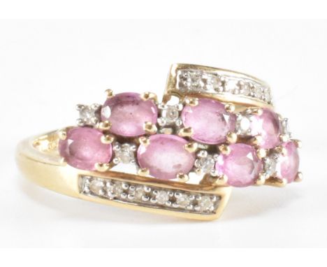 A hallmarked 9ct gold pink and diamond crossover ring. The ring being set with seven oval cut pink stones with diamond accent