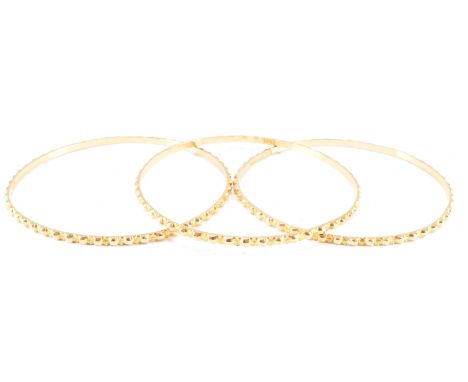 A group of three Middle Eastern gold bangle bracelets. The bracelet of round form with notched exteriors. Rubbed marks to the