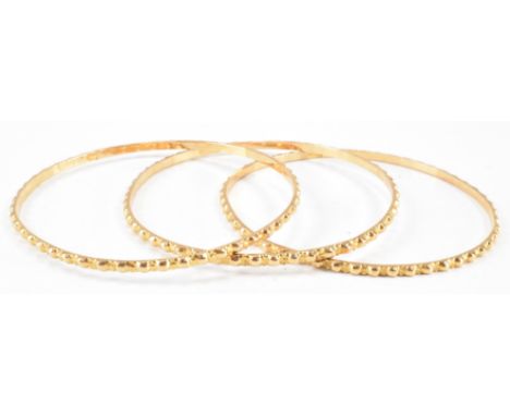 A group of three Middle Eastern gold bangle bracelets. All of round form with notched exteriors. Rubbed marks to the interior