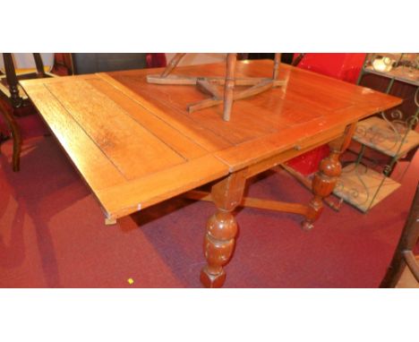 An early 20th century light oak draw dining table, having extended leave raised on turned x-framed stretchered supports 