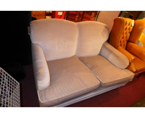 A contemporary grey two seater sofa supported by chrome casters 