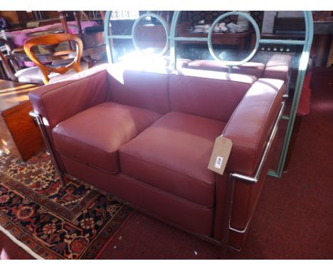 A Le Corbusier style two seater sofa upholstered in brown faux leather on chromed supports (slight tear)