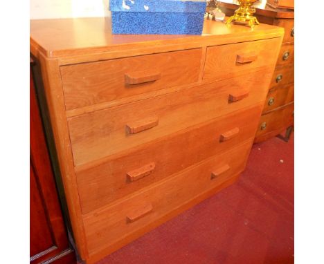 A mid century light oak chest of two short over three long raised on a plinth base