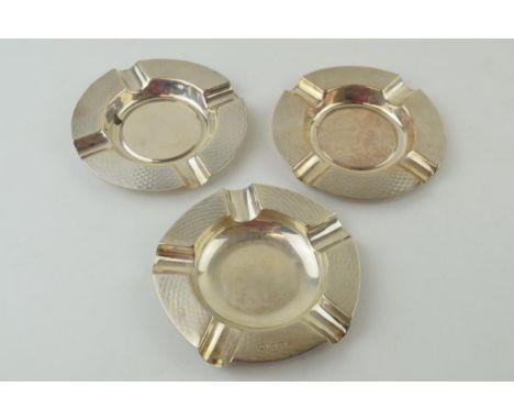 A pair of silver ashtrays, engineered design, Birmingham 1933, 11.5cm wide, with a similar singular item, marks rubbed, combi