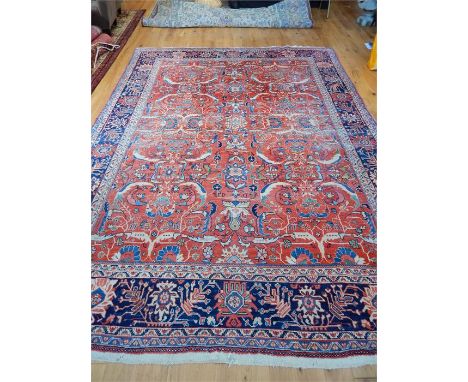 A large Persian carpet, with floral designs on a red field, surrounded by one frieze and four running borders (quite worn), 3