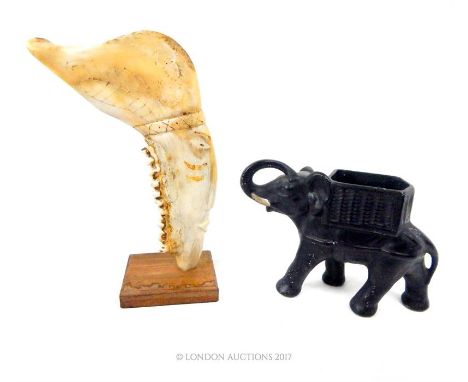 A painted ceramic model of an elephant, 17 x 25 x 9cm. with a Cuban sculpture formed of a carved cattle jawbone, on a wooden 