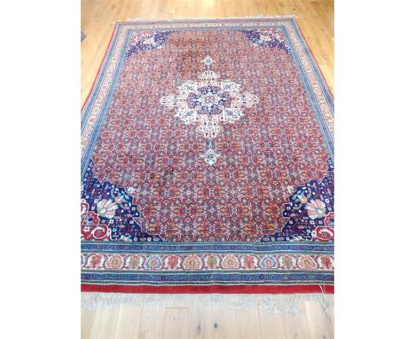 A fine Persian Kashan carpet, having a cream-coloured, central medallion on a red field with spandrels, surrounded by one fri