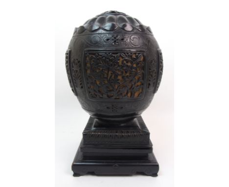 A Chinese bronzed table lamp cast and pierced with peonies and scrolls, raised on an ebonised stand, 32cm high