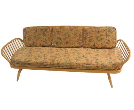 A light Ercol daybed with floral cushions with panel back and side spindles, 209cm wide This item is offered for sale as a wo