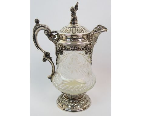 A silver plate mounted cut glass claret jug the silver plate with foliate embossing, face mask, stylised bird's head spout an