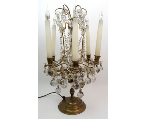 A gilded metal and glass table lamp festooned with cut and spherical glass drops, with faux candle bulb holders, 53 cm high