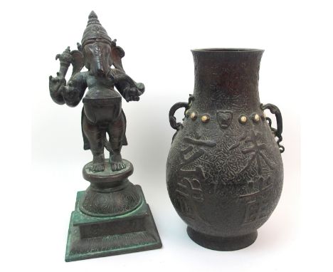 An Indian bronze of Ganesh standing on a circular pillar and square shaped base, decorated with scrolling foliage, 37cm high 