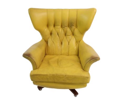 A 1960's yellow leather button back swivel rocker on a rosewood base, 92cm high A CITES Certificate is in place for this lot 