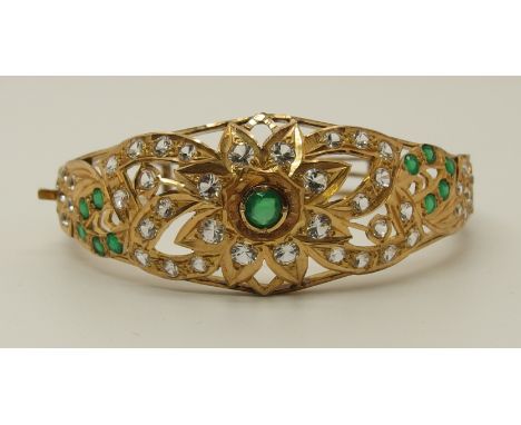 A bright yellow bangle set with green and clear gems in the Arabic style, inner diameters 5.7cm x 5.4cm, weight 27.5gms